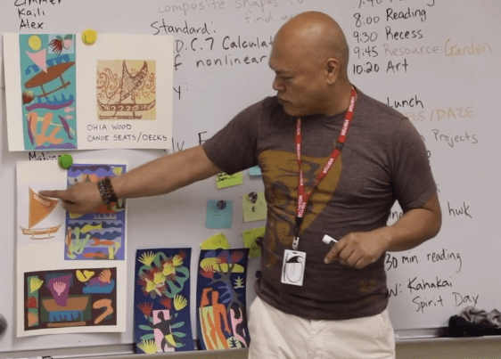 Male teacher in front of a whiteboard covered in art