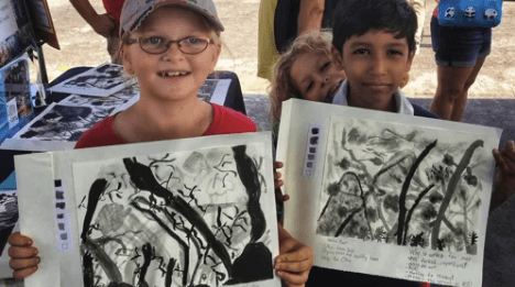 Two kids holding up pieces of art