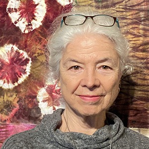 Ellen Crocker in front of a quilted wall hanging