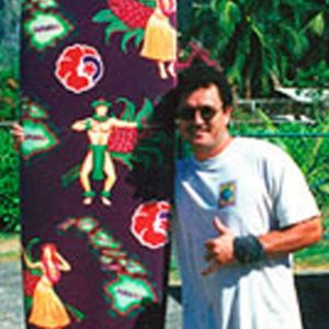 Jeff Pagay standing next to a colorful surfboard, making a shaka sign.