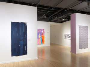 View of museum gallery showing artworks mounted on walls.