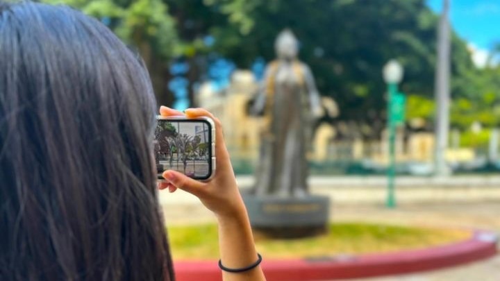 Person holding smartphone up in front of statue
