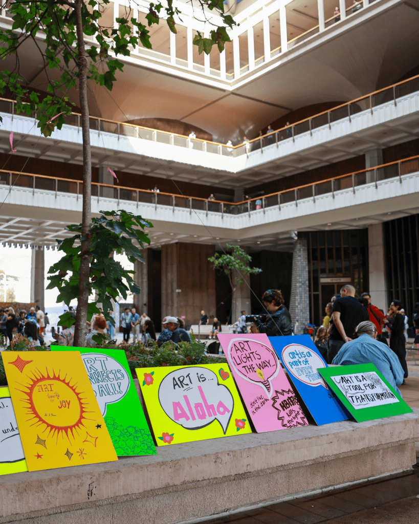 Row of colorful, hand-lettered arts advocacy signs at the Hawaii State Capitol.